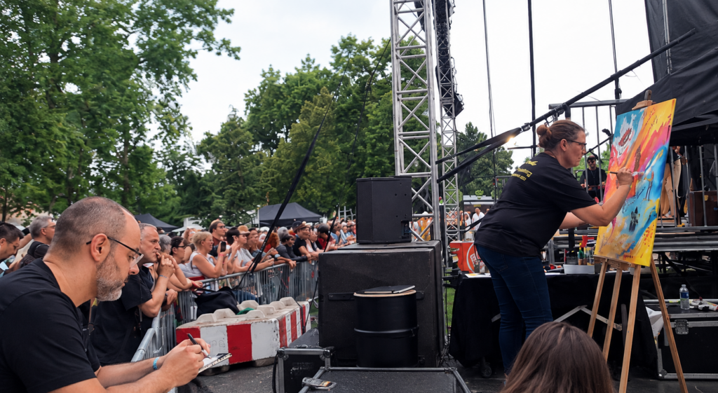 Carole Tournier réalisant un live-painting pendant un concert rock de festival