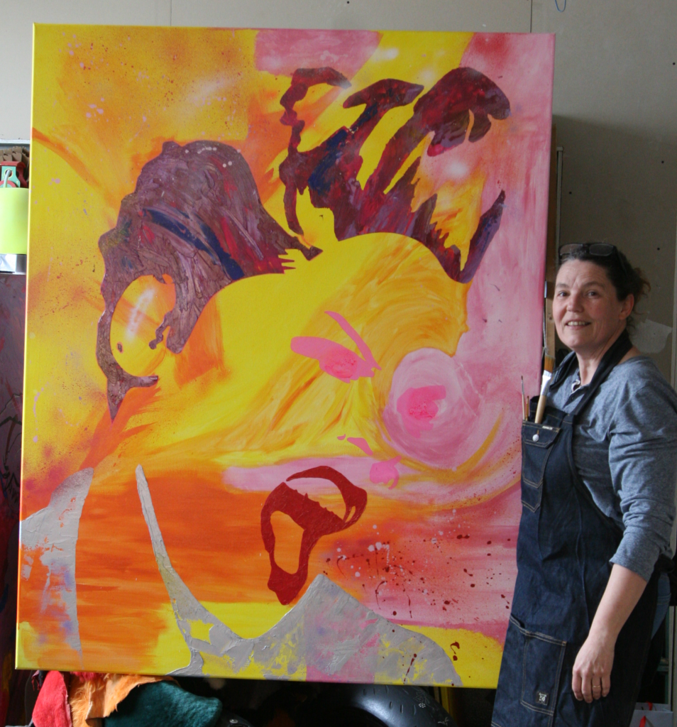 Carole Tournier dans son atelier d'artiste peintre, à côté de son tableau, cri d'amour.